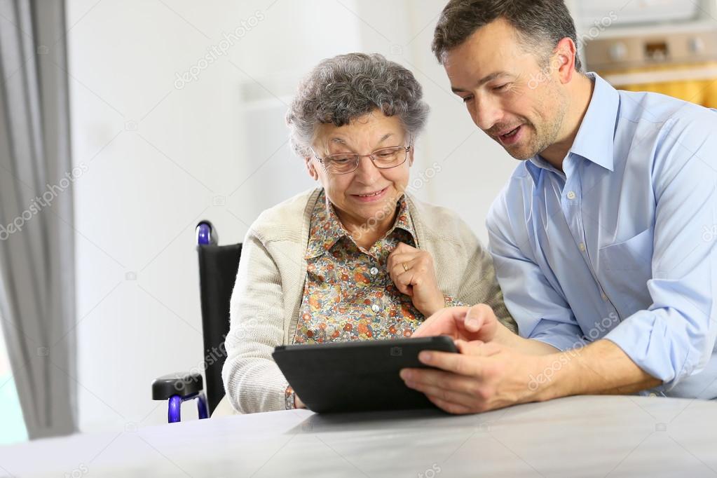 Man with elderly woman using tablet