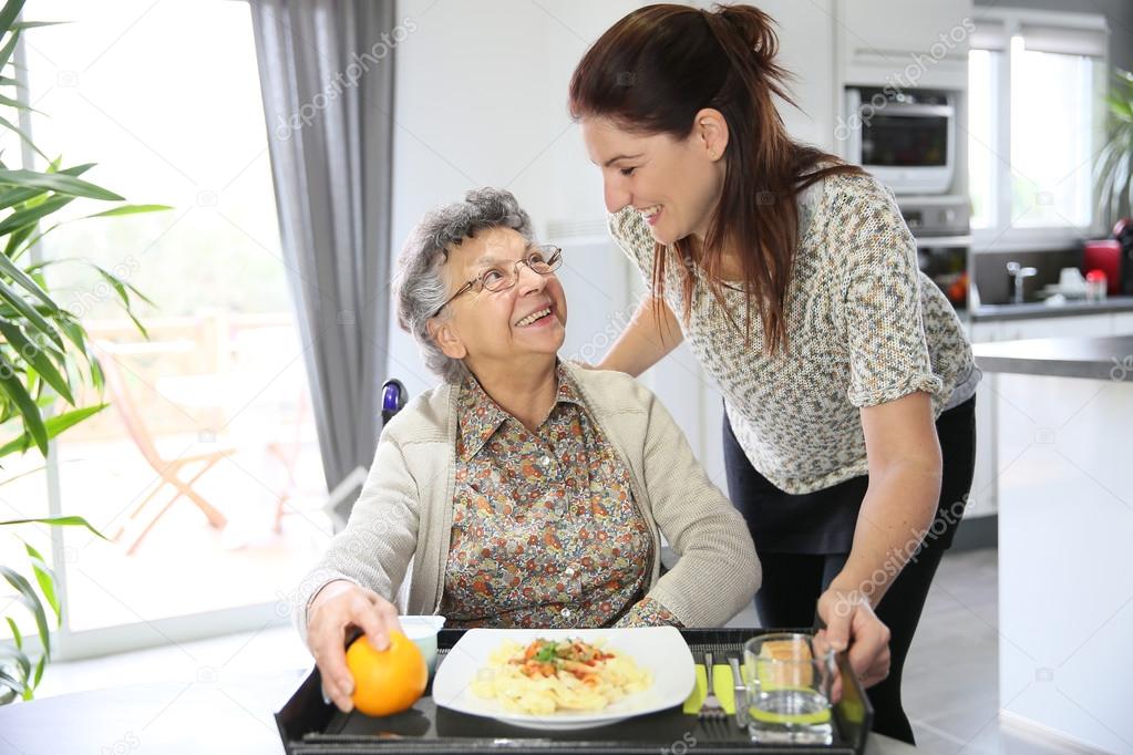 Home carer preparing lunch for woman