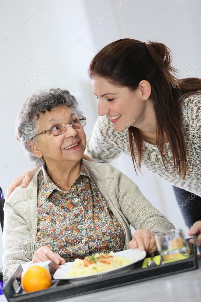 Home carer preparing lunch for woman