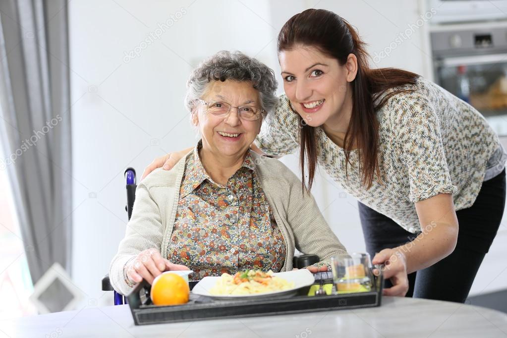 Home carer preparing lunch for woman