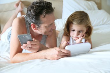 Adam akıllı telefon ve kızı tablet ile