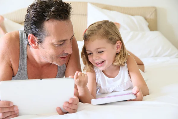 Man with smartphone and daughter with tablet