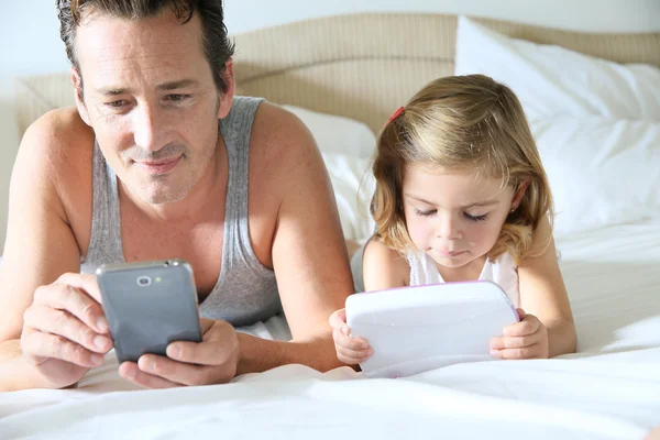Man med smartphone och dotter med tablett — Stockfoto