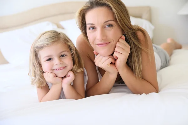 Flicka med mamma om på sängen — Stockfoto