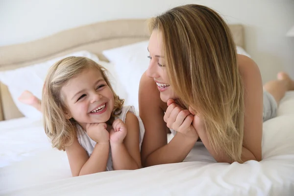 Flicka med mamma om på sängen — Stockfoto