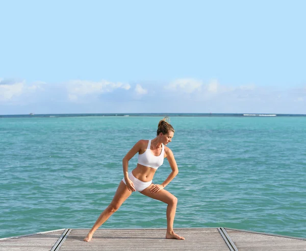 Kvinnan gör stretching övningar av havet — Stockfoto