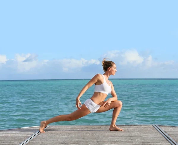 Woman doing stretching exercises by sea — Stock Photo, Image