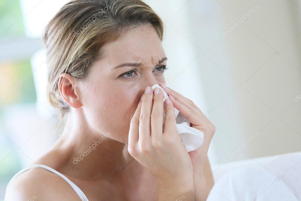 Woman with allergy blowing nose