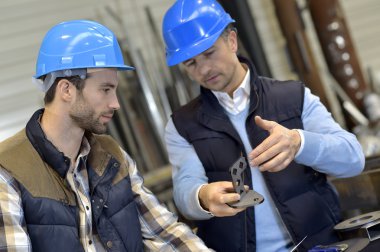 Engineer with worker checking on production