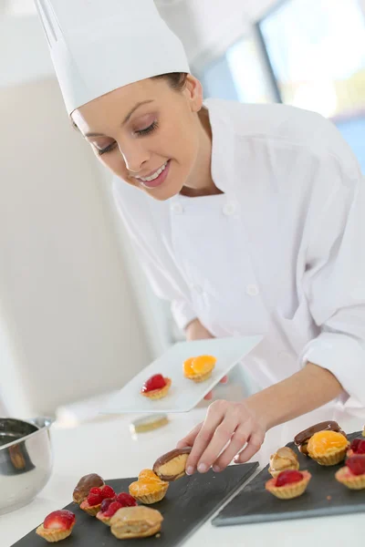 Pastry-cook preparing plate of cake bites — Stock Photo, Image