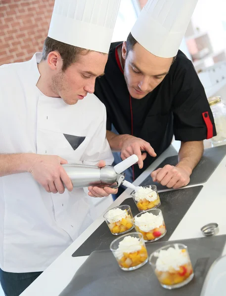 Cook preparing dessert with chef — Stock Photo, Image