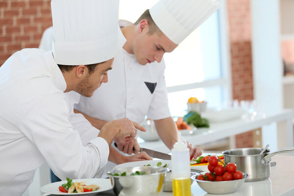 Chef training student in restaurant kitchen
