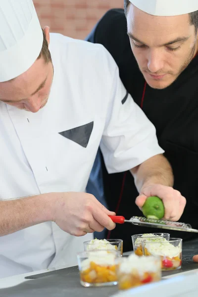 Cook preparing dessert with chef — Stock Photo, Image