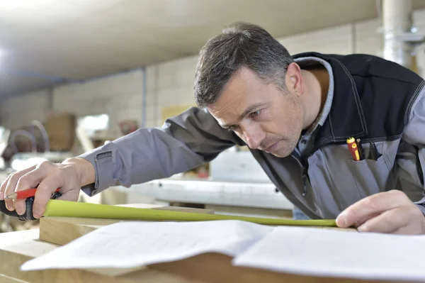 Worker measuring wood plank — Stock Photo, Image