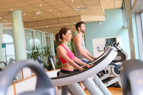 Casal trabalhando na máquina cardio — Fotografia de Stock