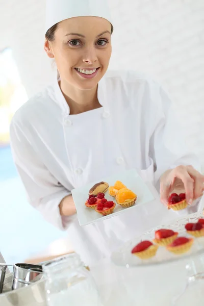 Pastry-cook preparing plate of cake bites — Stock Photo, Image