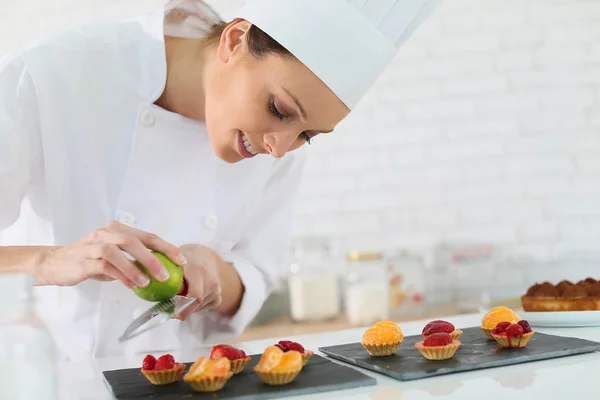 Pastry-cook shredding lemon zest — Stock Photo, Image