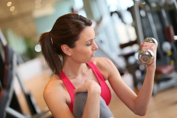 Spor salonunda dambılları kaldıran kadın. — Stok fotoğraf