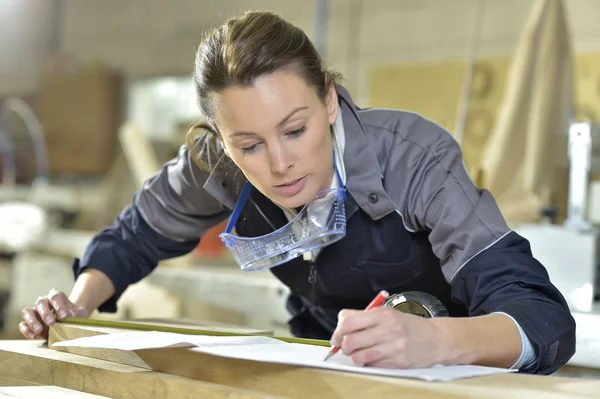 Arbeiter misst Holzplanke — Stockfoto