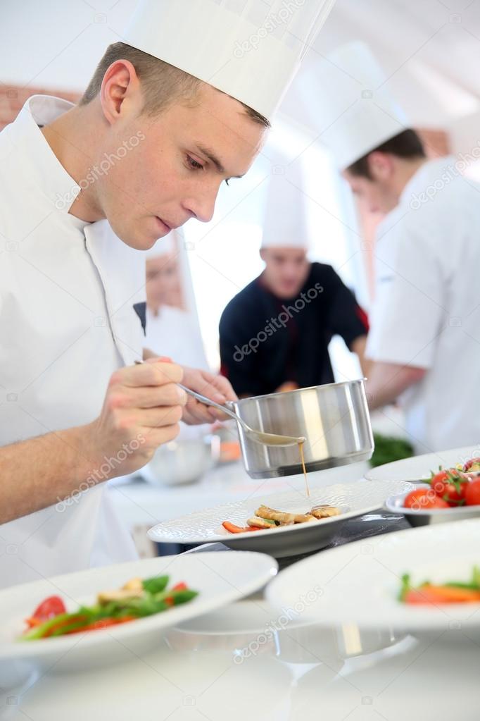 Cook pouring sauce on dish