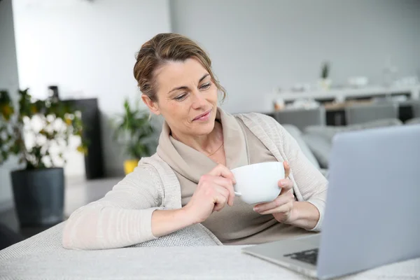 Mulher com café na frente do laptop — Fotografia de Stock