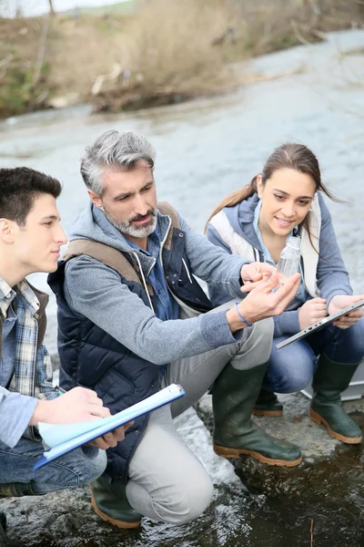 Biólogo con estudiantes analizando el agua del río — Foto de Stock