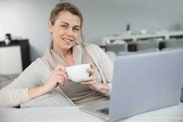 Donna con caffè davanti al computer portatile — Foto Stock