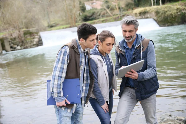 Profesional con estudiantes de pie junto al río — Foto de Stock