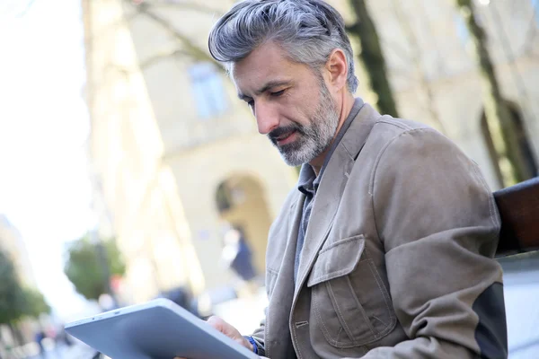 Man websurfing med tablett på bänk — Stockfoto