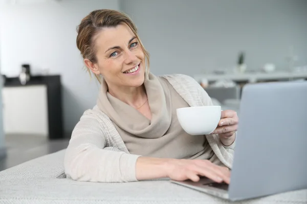 Donna con caffè davanti al computer portatile — Foto Stock