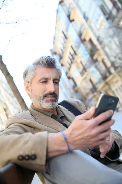 Cara usando smartphone no banco — Fotografia de Stock