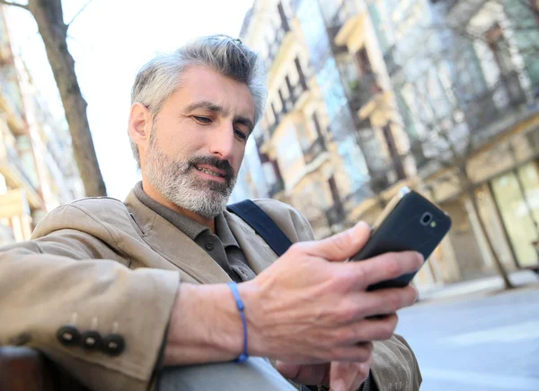 Guy pomocí smartphone na lavičce — Stock fotografie