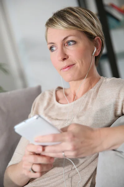 Vrouw met behulp van smartphone en koptelefoon — Stockfoto