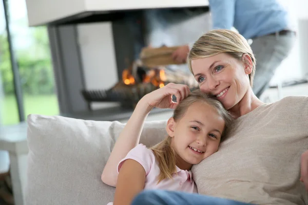 Mother and daughter relaxing by fireplace — Stock Photo, Image