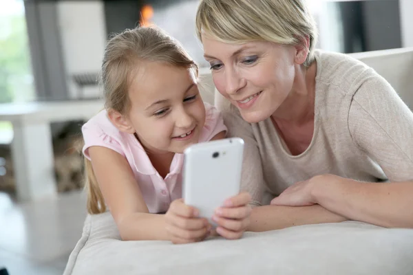 Мать и девочка играют со смартфоном — стоковое фото