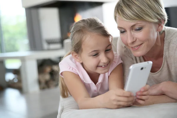 Mor och flicka som leker med smartphone — Stockfoto