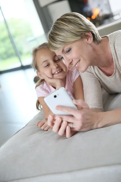 Мать и девочка играют со смартфоном — стоковое фото