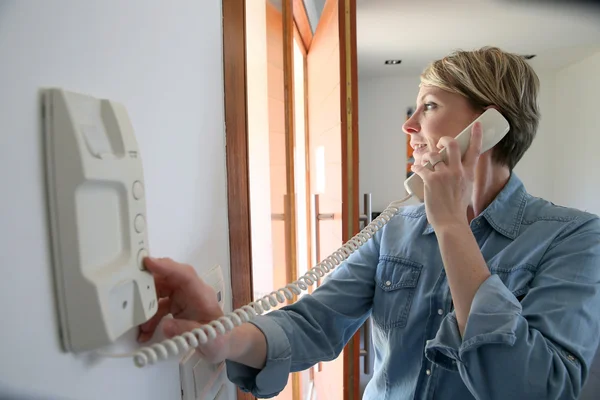 Woman answering intercom — Stock Photo, Image