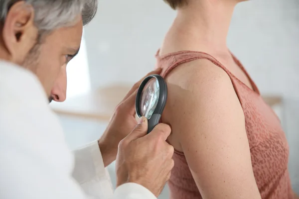 Dermatologist looking at woman's mole — Stock Photo, Image