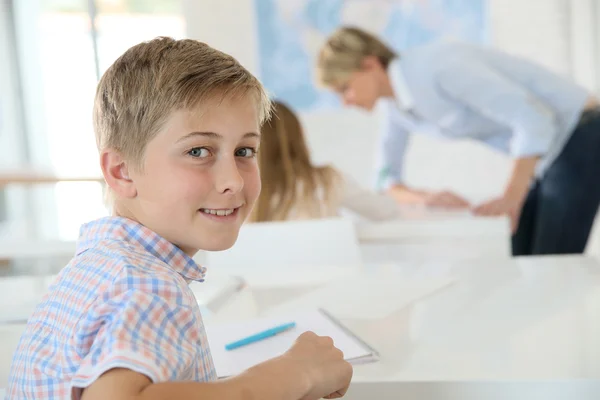 Smiling schoolboy in classroom — Stock Photo, Image