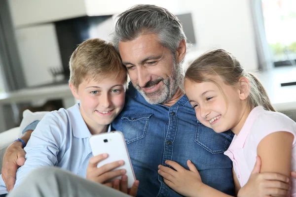 Мужчина с детьми играет со смартфоном — стоковое фото