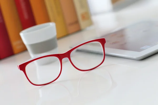Eyeglasses on table by tablet — Stock Photo, Image
