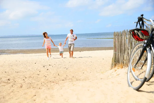 Familie läuft auf einem Sandstrand — Stockfoto