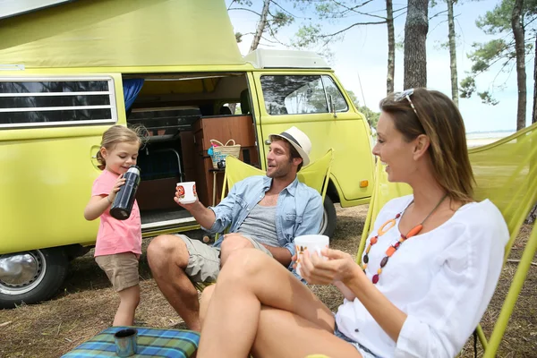 family relaxing by camper van