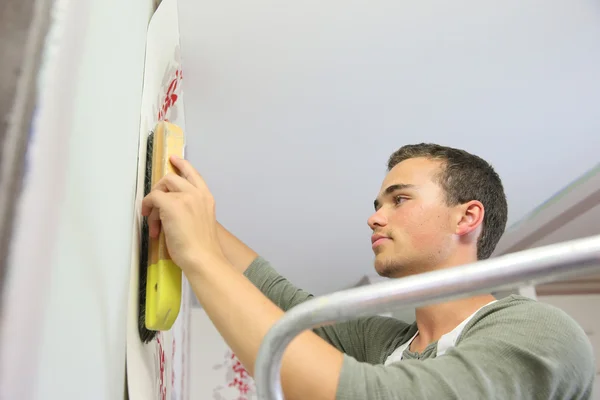 Apprentice learning how to put wallpaper — Stock Photo, Image