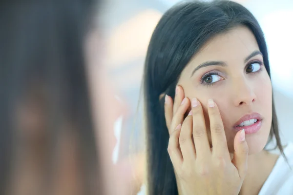 Girl looking at skin in mirror — Stock Photo, Image