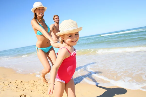 Fille courir sur la plage avec les parents — Photo