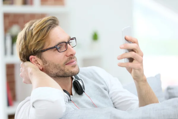 Man kopplar av i soffan med smartphone — Stockfoto