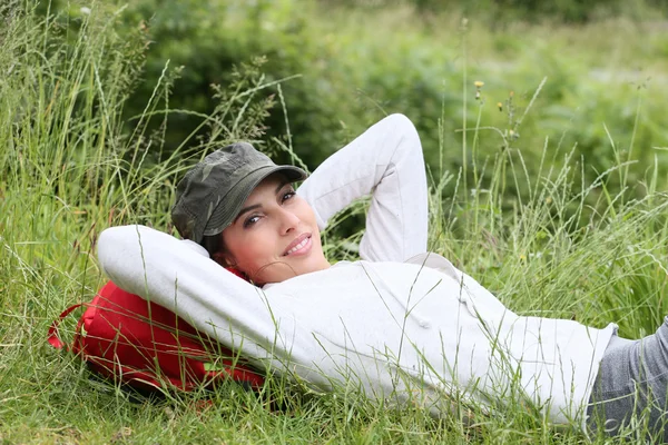 Mulher relaxante na grama no dia de caminhadas — Fotografia de Stock