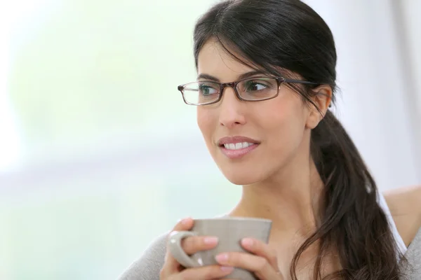 Дівчина в окулярах тримає чашку — стокове фото